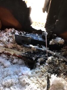 Burnt insulation and charred electrical wiring are visible in an attic space, with significant fire damage to the surrounding materials.