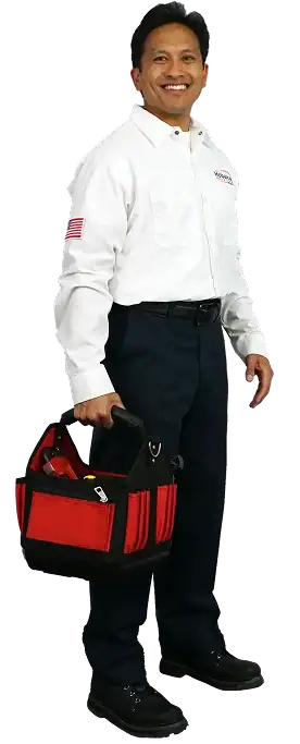 Smiling man in a white shirt with an American flag patch, dark pants, and black shoes holding a red and black tool bag.