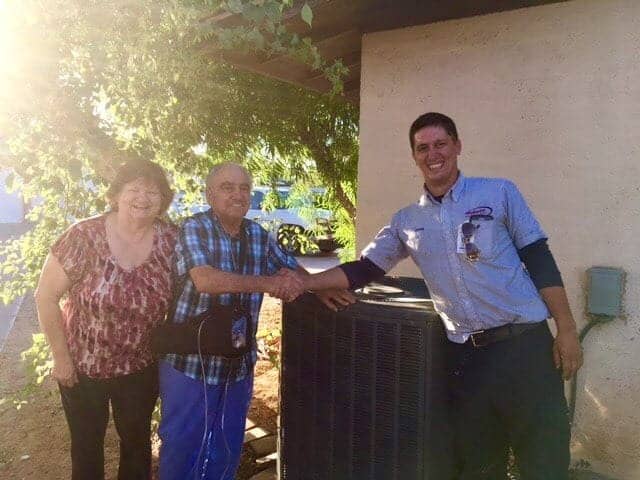 %Title% | Hobaica Services Two people smile while standing beside a service technician who is shaking hands with one of them next to an outdoor HVAC unit.