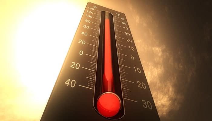 A thermometer showing high temperatures near 40°C or 100°F, with a bright sun and hazy sky in the background.