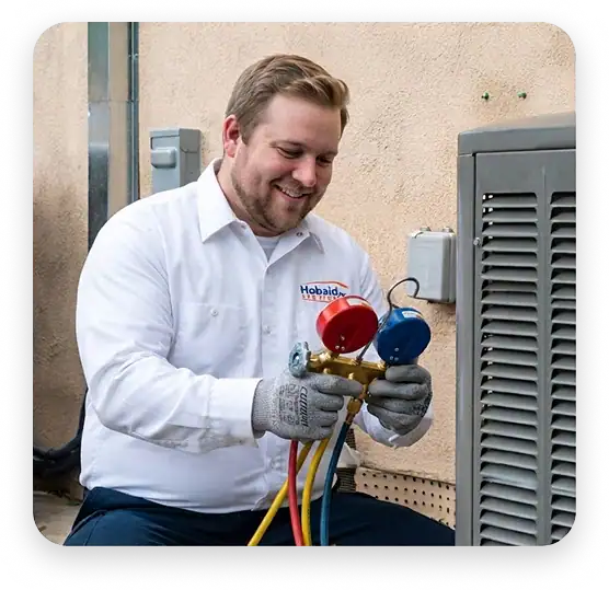 A technician in a white shirt uses a manifold gauge to check an outdoor HVAC unit.
