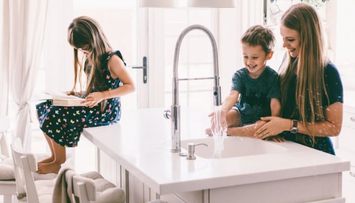 Family In Kitchen With Water Running